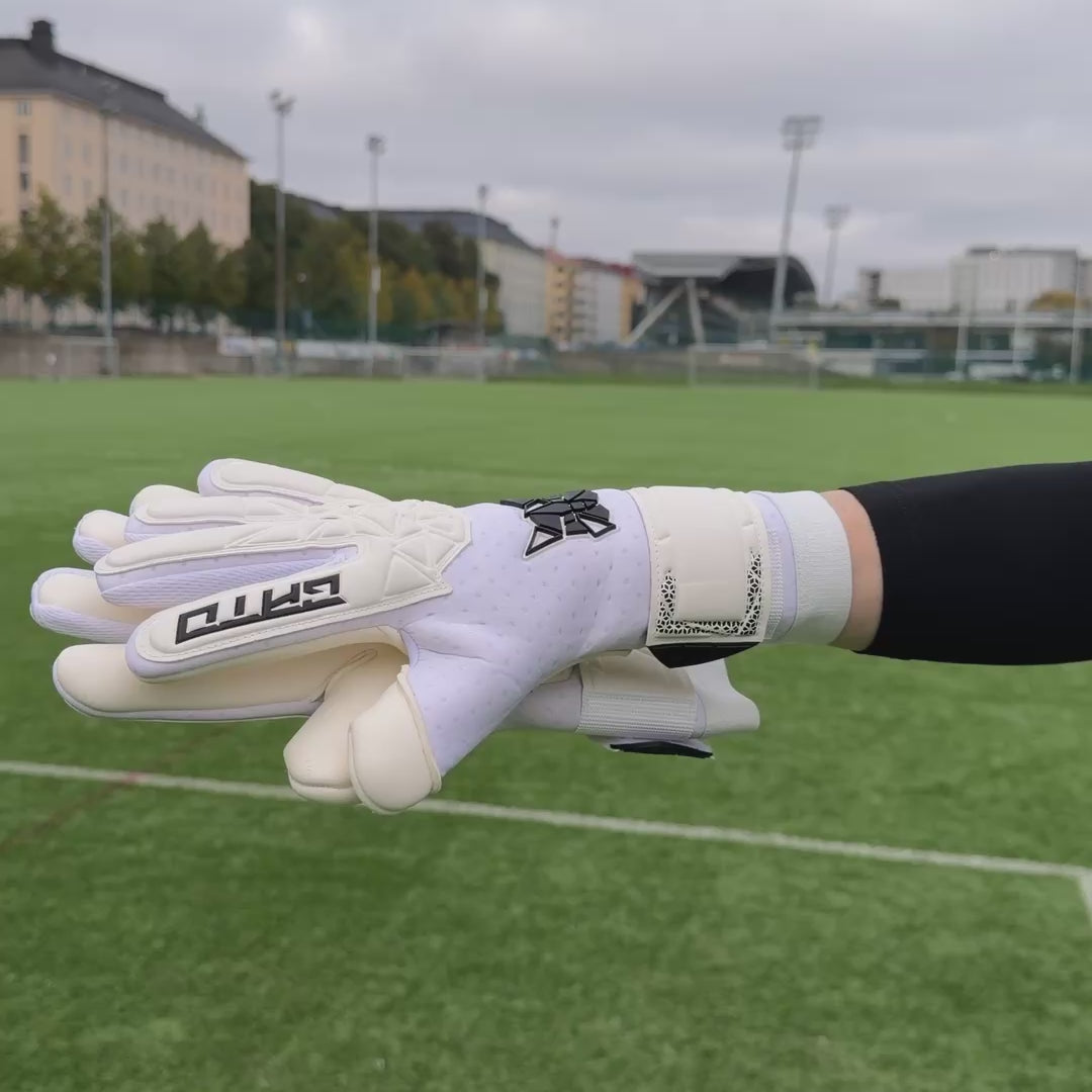 Goalkeeper putting on white GATO Classic Match goalkeeper gloves on an artificial turf pitch